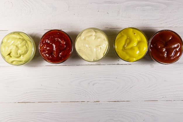 Conjunto de salsas en mesa de madera blanca. Vista superior, espacio de copia