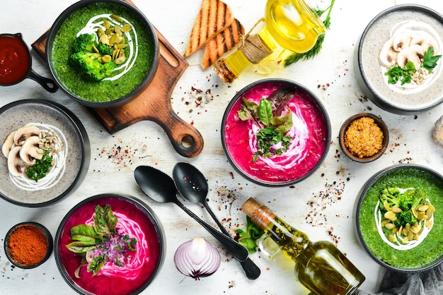 Conjunto de sopas de colores sobre fondo blanco de madera Sopa de remolacha sopa de crema de brócoli y sopa de champiñones Vista superior