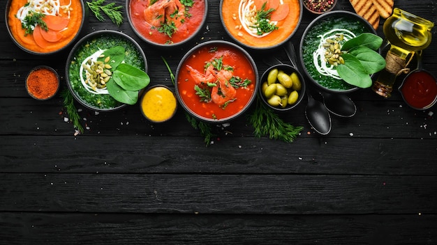 Conjunto de sopas de colores Sopa de espinacas sopa de crema de tomate y sopa de puré de zanahoria Comida saludable Sobre un fondo de piedra negra