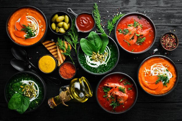 Conjunto de sopas de colores Sopa de espinacas sopa de crema de tomate y sopa de puré de zanahoria Comida saludable Sobre un fondo de piedra negra