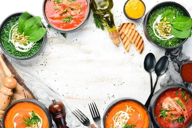 Conjunto de sopas sabrosas de colores sobre fondo blanco de madera Sopa de espinacas, tomate y zanahoria Comida saludable