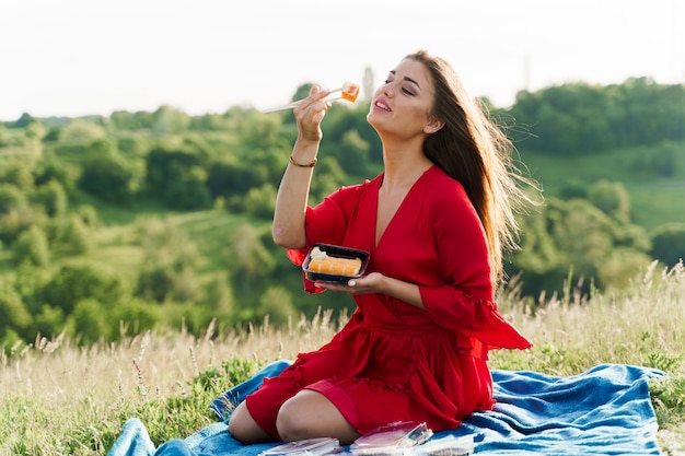 Foto conjunto de sushi y chica en colinas verdes.