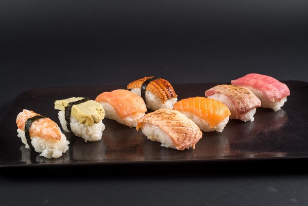 Conjunto de sushi sashimi sobre fondo negro