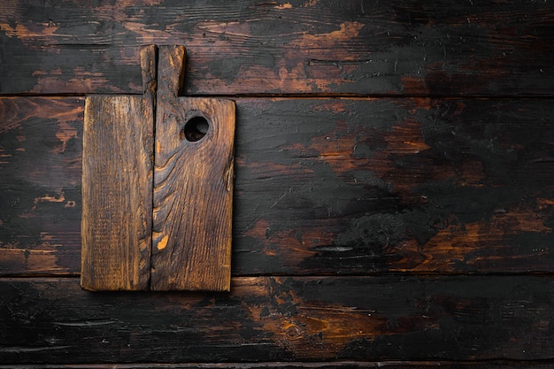 Conjunto de tabla de cortar antigua, vista superior plana, con espacio de copia para texto o comida, sobre fondo de mesa de madera oscura antigua