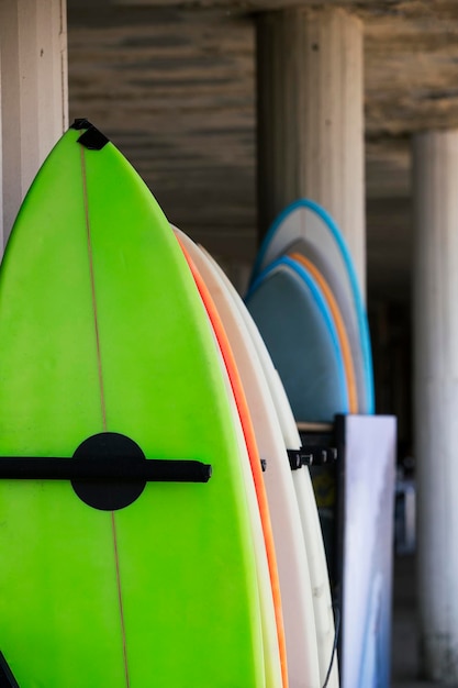 Foto conjunto de tablas de surf de diferentes colores en una pilatablas de surf en la playa de arena para alquilar clases de surf en la playa