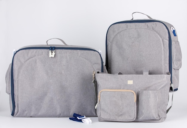 Conjunto de tiro de estudio de primer plano de tres bolsos de accesorios para bebés recién nacidos de utilidad multiusos multifunción grande de color gris con asa de bolsillos de estiramiento y correa de hebilla de seguridad sobre fondo blanco