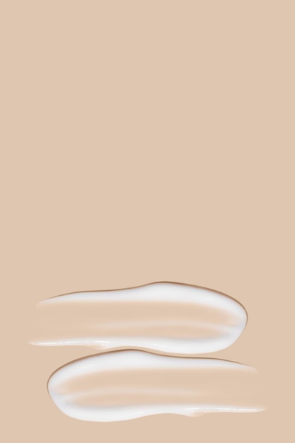 Foto un conjunto de trazos de crema blanca sobre un fondo beige.