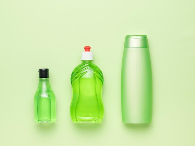 Un conjunto de tres botellas de detergentes sobre un fondo verde Kit de limpieza