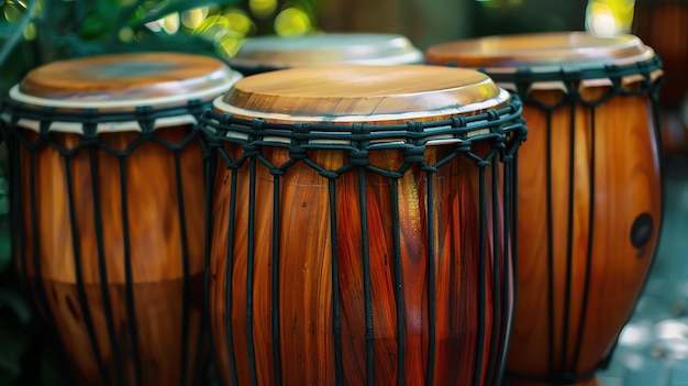 Un conjunto de tres tambores djembe africanos con un acabado de madera natural y cuerdas negras