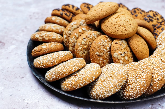 Conjunto de varias galletas de estilo americano sobre un fondo de hormigón ligero. Galletas de mantequilla con confeti, semillas de sésamo, mantequilla de maní, avena y galletas de chispas de chocolate.