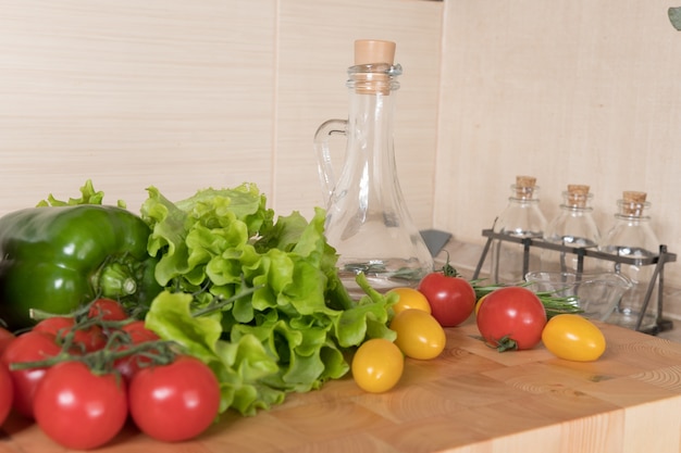 Conjunto de variedad de vegetales en una tabla de cortar en la cocina. Conceptos de alimentación saludable. Ingredientes para ensalada, tomates, pimiento, aceite de oliva, especias.