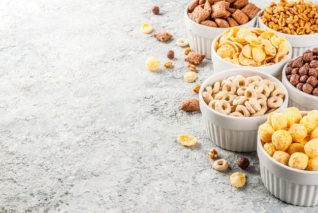 Conjunto de varios cereales de desayuno copos de maíz, hojaldres, paletas, espacio de copia de mesa de piedra gris