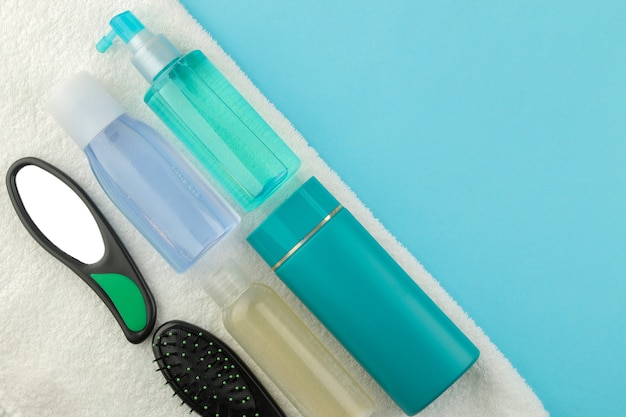 Un conjunto de varios peines y espejo y cosmético para el cabello sobre una toalla blanca sobre un fondo azul brillante. vista desde arriba. con espacio para texto
