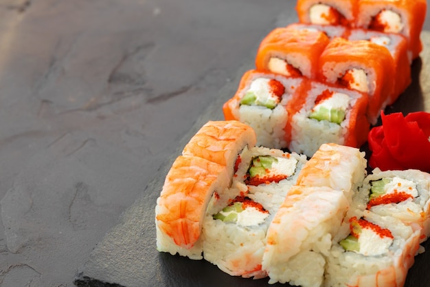 Foto conjunto de varios rollos de sushi servidos en mesa gris