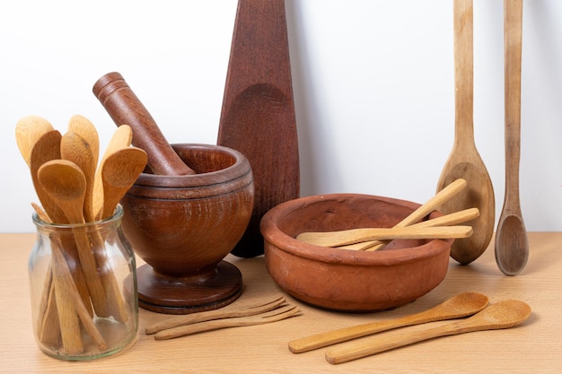 Conjunto de varios utensilios de cocina tradicionales hechos de madera y un cuenco de arcilla.