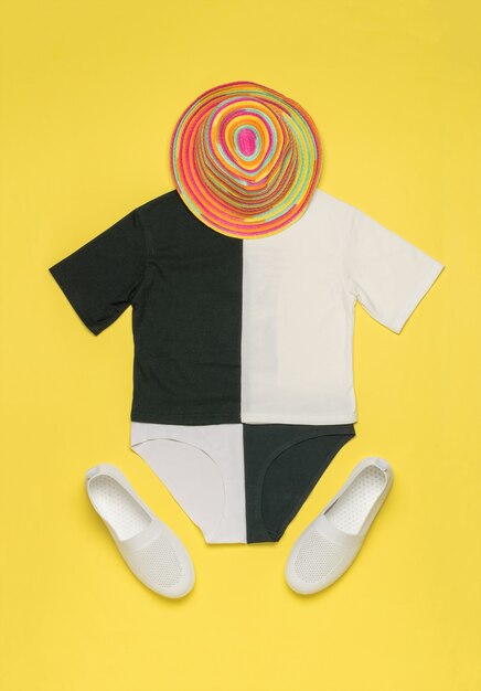 Conjunto de verano blanco y negro, sombrero y zapatillas sobre una superficie amarilla. El concepto de vacaciones de verano.