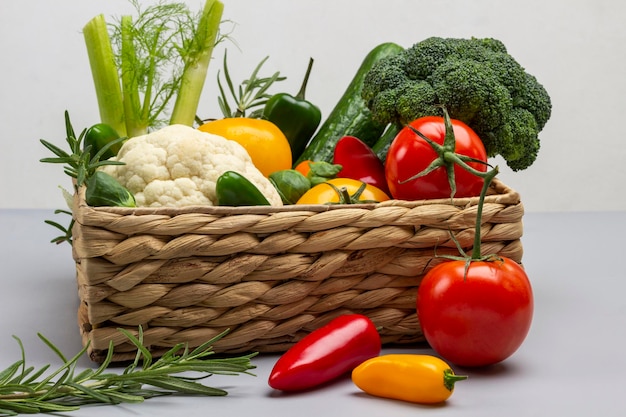 Conjunto de verduras coloridas en cesta de mimbre. Tomates frescos y pimientos en la mesa. alimentos de dieta saludable