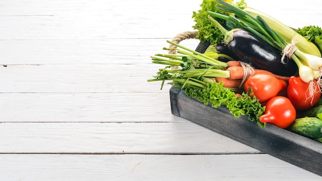 Un conjunto de verduras frescas en una caja de madera Sobre un fondo de madera Vista superior Espacio de copia