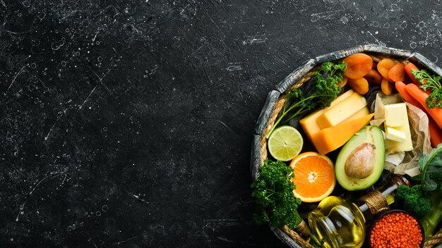 Conjunto de verduras, frutas y alimentos sobre un fondo de piedra negra Los alimentos son ricos en vitamina A Vista superior Espacio libre para el texto