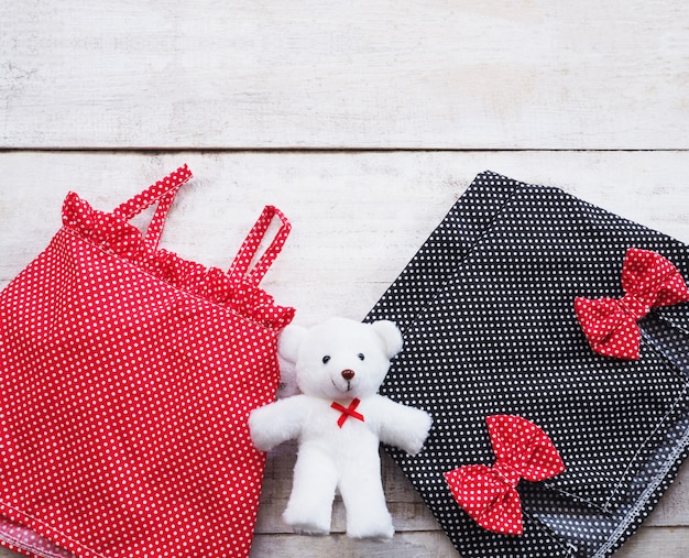 Conjunto vestido de verão da menina crianças e boneca de pelúcia em fundo de madeira