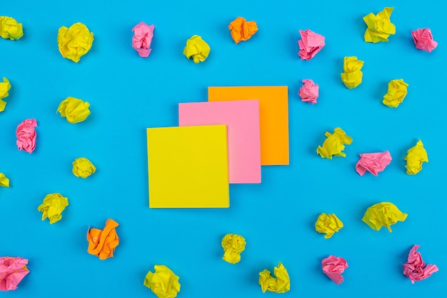 Conjuntos de colores de adhesivos amarillos, rosados, naranjas superpuestos uno a uno ubicados en el centro con adhesivos arrugados de diferentes colores alrededor. De cerca. Set para notas.