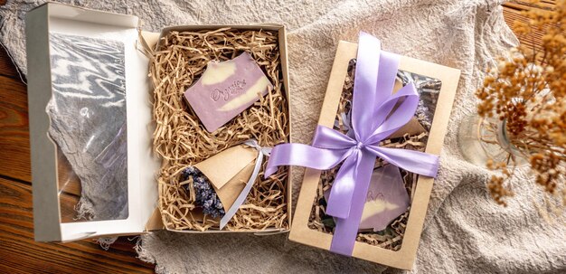 Conjuntos de presentes bonitos feitos à mão de um pedaço de sabão natural e um buquê de lavanda em uma caixa de artesanato e cuidadosamente amarrados com uma fita