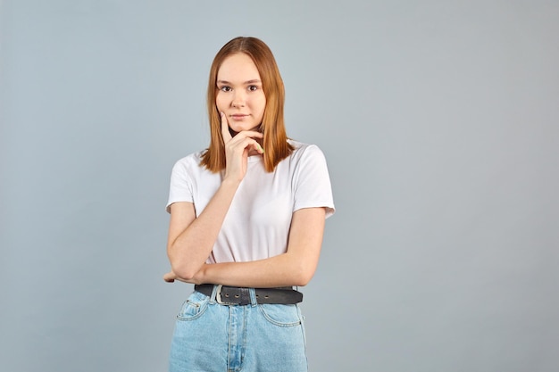 Foto conmocionada chica divertida de pie aturdida sorprendida reaccionando sobre fondo grispánico conmocionada linda mujer joven europea