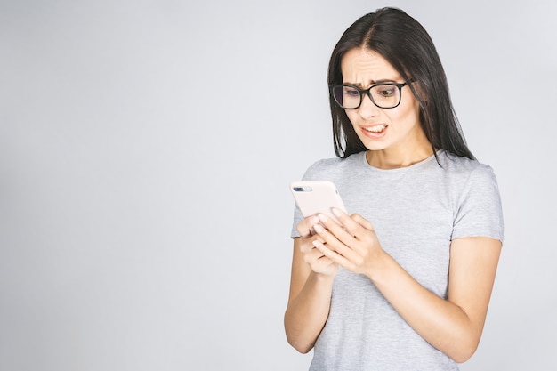 Conmocionada joven mirando noticias de lectura de teléfono móvil