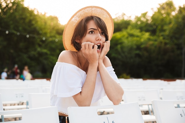 Conmocionada joven con sombrero de verano mirando lejos