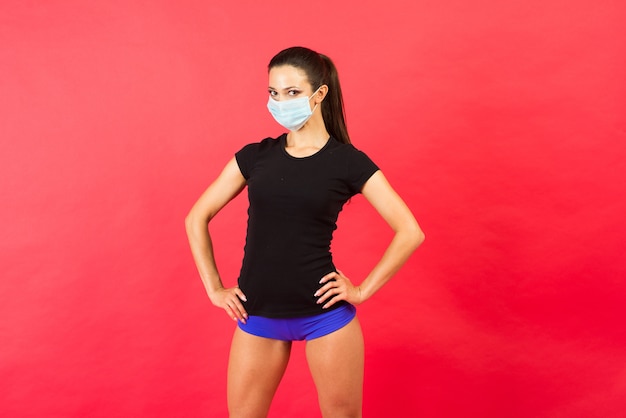 Conmocionada mujer joven fitness en ropa deportiva mascarilla estéril trabajando aislado sobre fondo amarillo retrato de estudio.