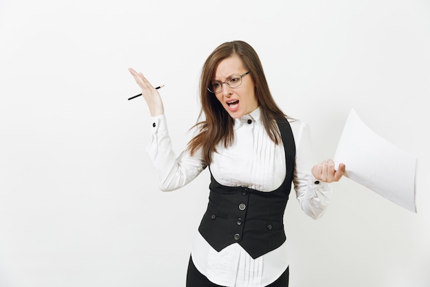 Conmocionada perpleja enojada caucásica joven mujer de negocios de cabello castaño en traje negro, camisa blanca, gafas con documentos de trabajo aislados en la pared blanca