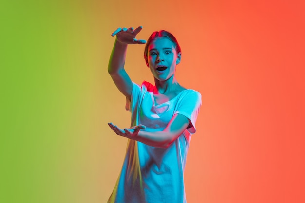 Conmocionado la celebración de espacio en blanco Retrato de niñas caucásicas jóvenes en estudio verde degradado naranja