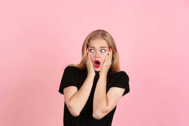 Conmocionado. Retrato de joven mujer emocional gesticulando aislado sobre fondo rosa studio. Las emociones humanas, la expresión facial, las ventas, el concepto publicitario. Rubia modelo bonita caucásica gesticulando. Copyspace.