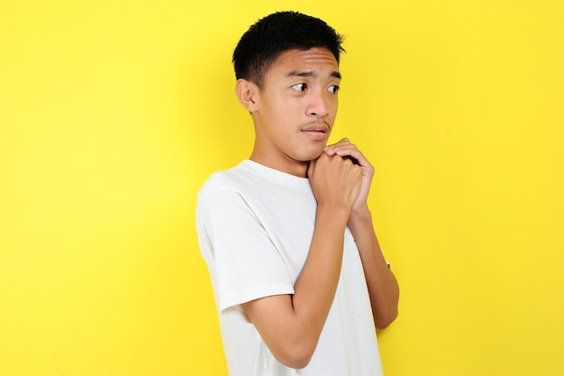 Conmocionado rostro de hombre asiático con camisa blanca sobre fondo amarillo.