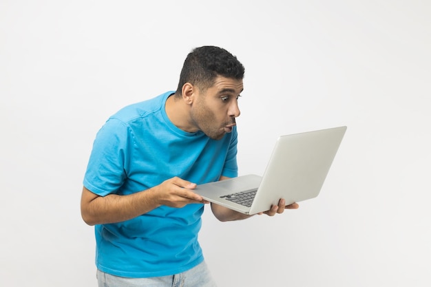 Conmocionado sorprendido hombre ve algo asombrado en la pantalla del portátil mirando el monitor con ojos grandes