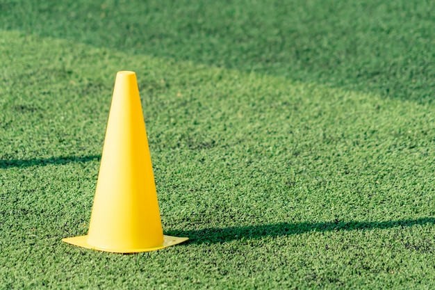 Cono de entrenamiento de fútbol amarillo en campo de hierba