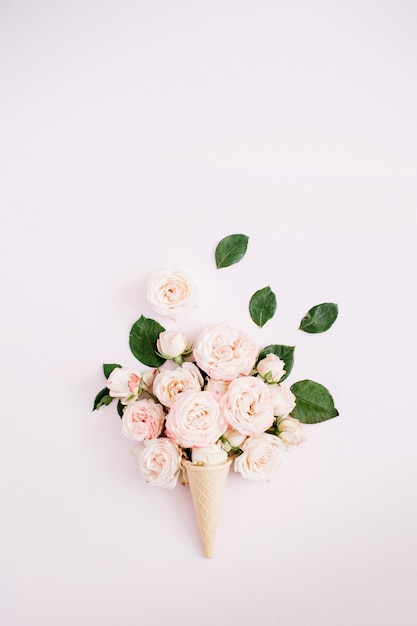 Cono de galleta con bouquet de rosas grandilocuentes sobre rosa pastel pálido