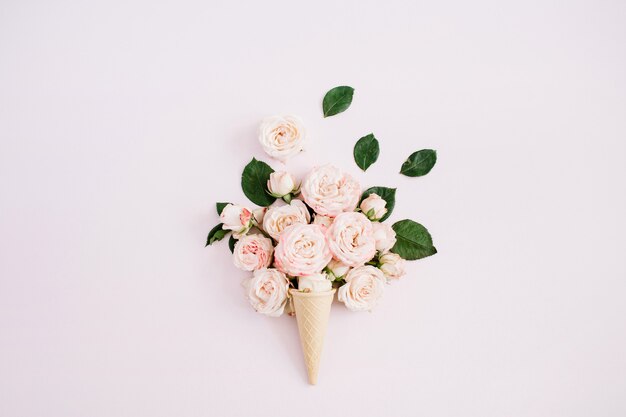 Cono de galleta con bouquet de rosas grandilocuentes sobre rosa pastel pálido