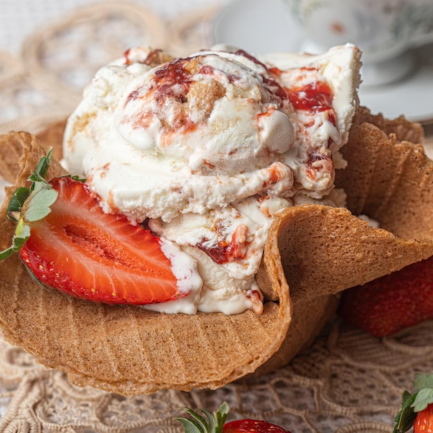 Un cono de galleta con fresas y una fresa encima.