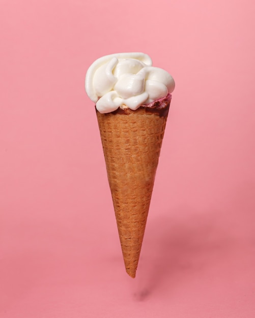 Cono de galleta de helado de vainilla aislado sobre fondo rosa