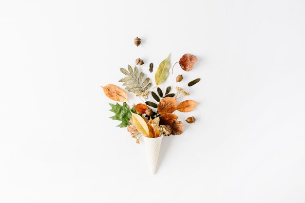 Cono de galleta con ramo de hojas secas de otoño en blanco