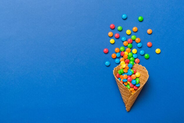 Cono de gofre lleno de dulces tradicionales variados que caen sobre fondo de color con espacio para copiar Concepto de venta de felices fiestas