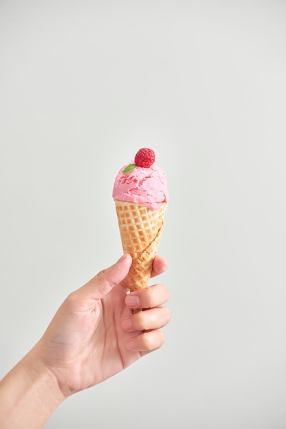 Cono de helado aislado. La mujer que sostiene el helado con la mano.