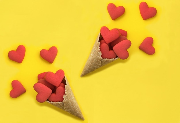 Cono de helado con galletas en forma de corazón rojo sobre fondo amarillo Vista superior Espacio de copia