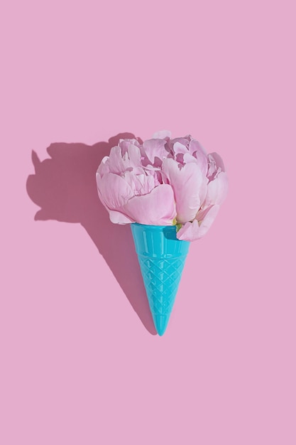 Cono de helado de juguete azul creativo con flor esponjosa de peonía rosa sobre fondo rosa mínimo con espacio de copia plano Idea de botánica para papel tapiz de verano o primavera o tarjeta de felicitación