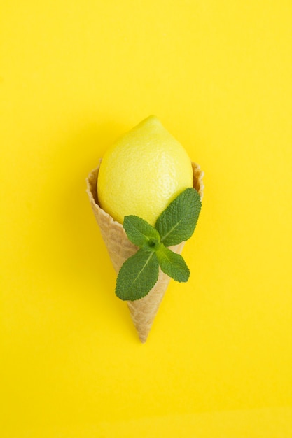 Cono de helado con limón y menta sobre fondo amarillo. Ubicación vertical. Copie el espacio.