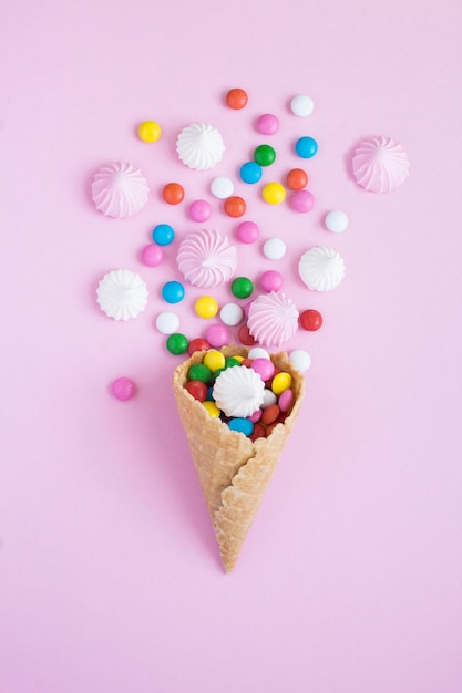 Cono de helado con merengue y dulces en el fondo rosa Vista superior Ubicación vertical