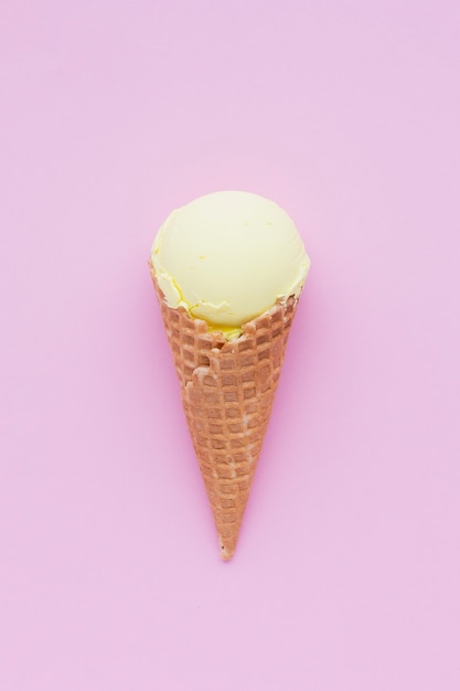 Cono de helado de sabor a limón sobre fondo rosa