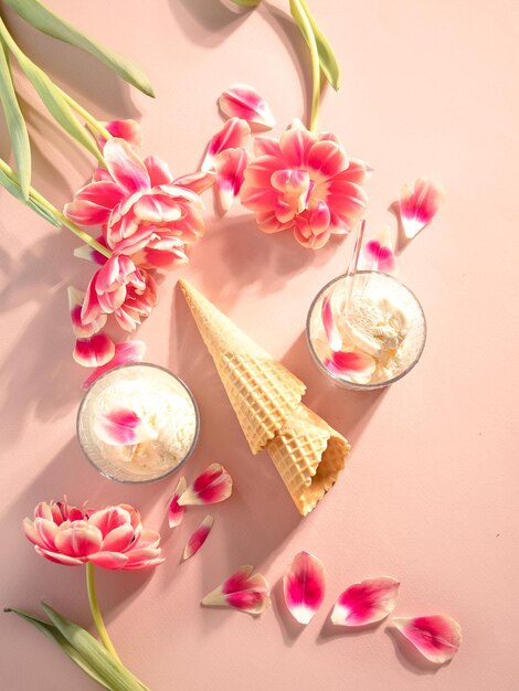 Cono de helado y sundae con flores rosas y pétalos concepto de verano plano