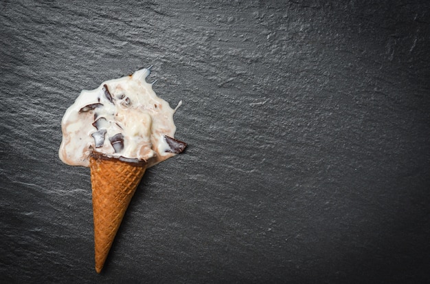 Cono de helado de vainilla con chocolate que gotea bolas de fusión de helado que fluye